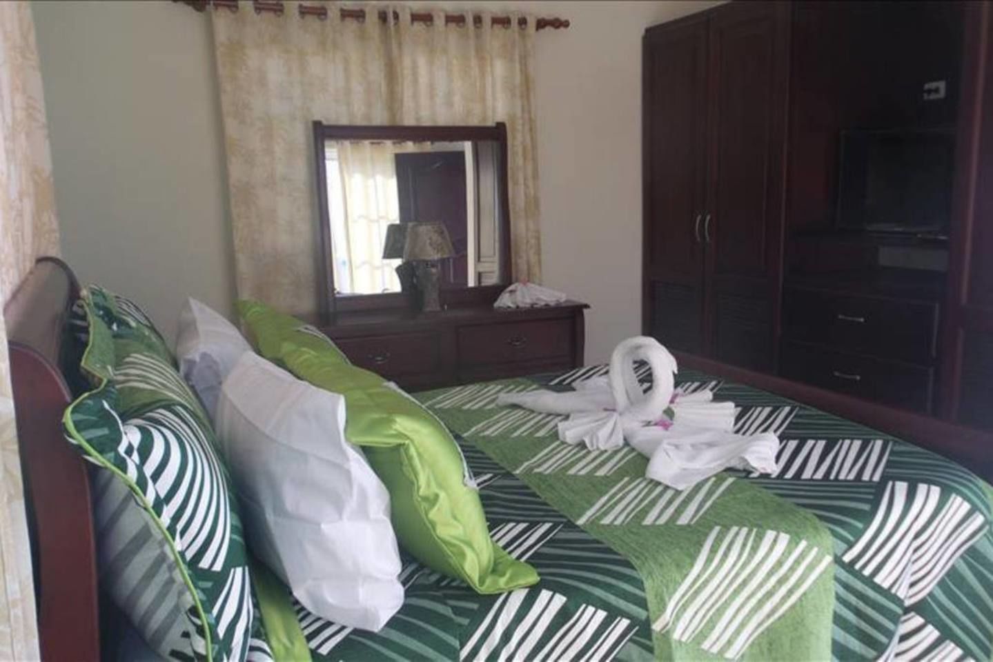 Ein Hotelzimmer mit Bett, Kommode, Spiegel und Kleiderschrank.