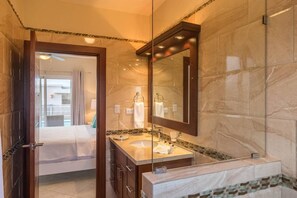 A hotel bathroom with a marble vanity, a large mirror, and a glass shower enclosure. - A Great Place to Relax, Sunbathe and Enjoy Life (Sosúa)
