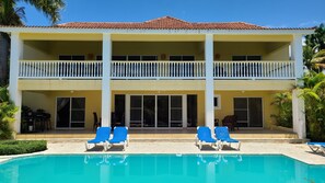 A two-story building with a swimming pool, a balcony, and a patio area with lounge chairs. - Villa Hermosa a Spacious Villa Close to Downtown (Sosúa)