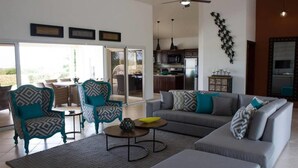 A modern living room with a grey sofa, teal armchairs, and a coffee table. - 4 Bed Villa Minutes From Downtown Sosua (Sosúa)