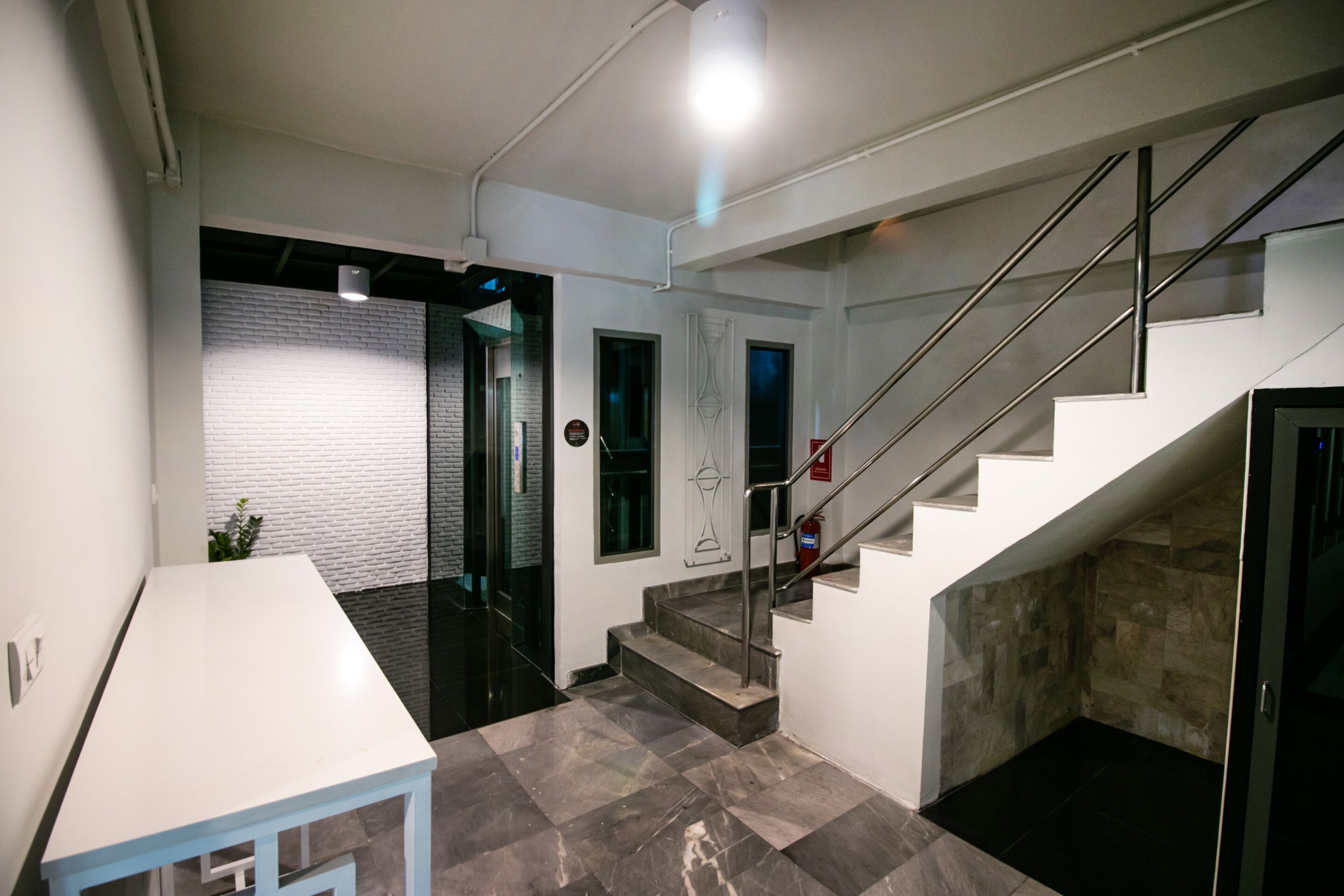 A modern interior with a staircase, a white wall with a brick pattern, and a door leading to another room.