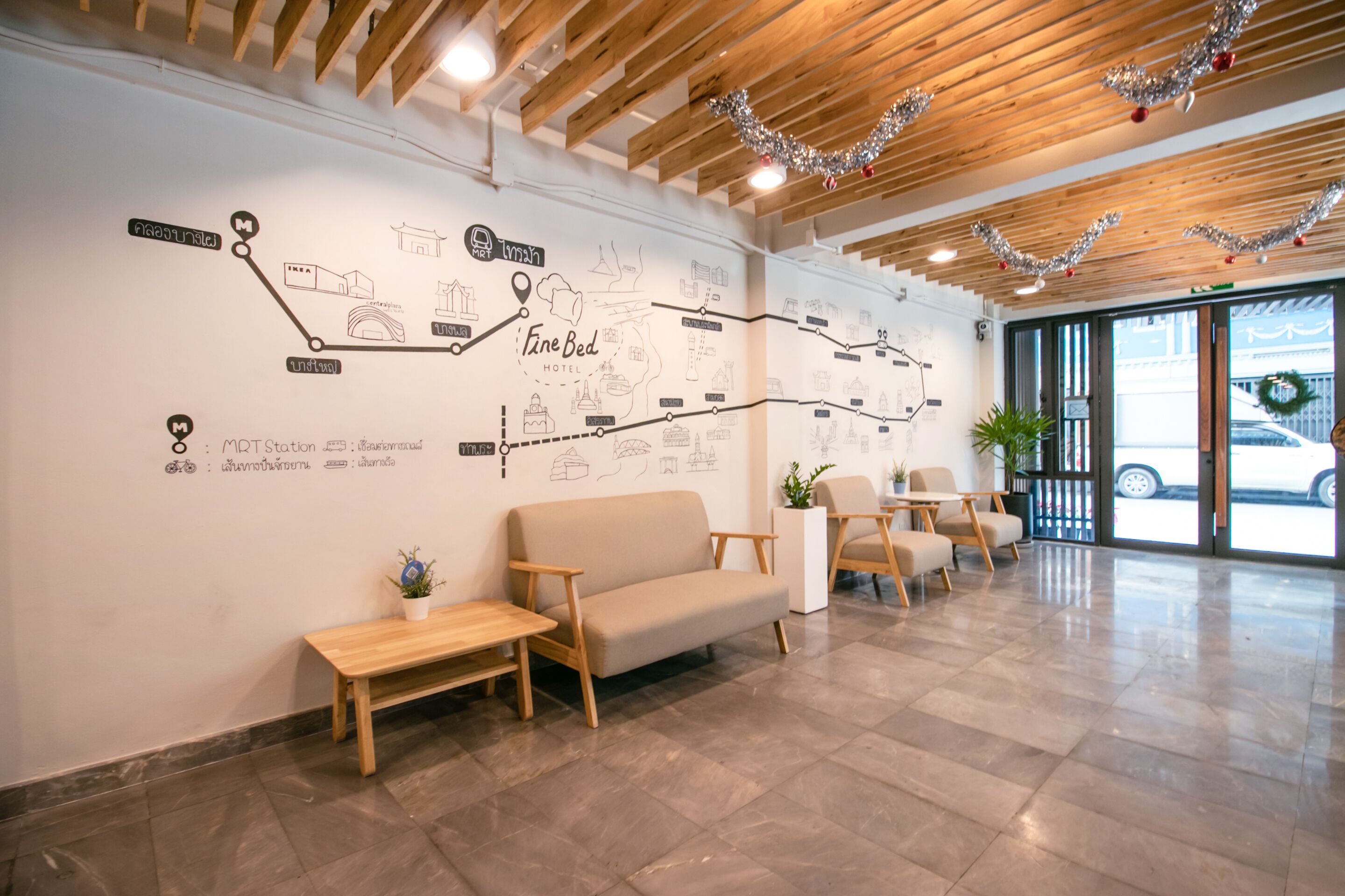 Zona de recepción de hotel con techo de madera, un gran mapa mural, asientos y vista a la calle.