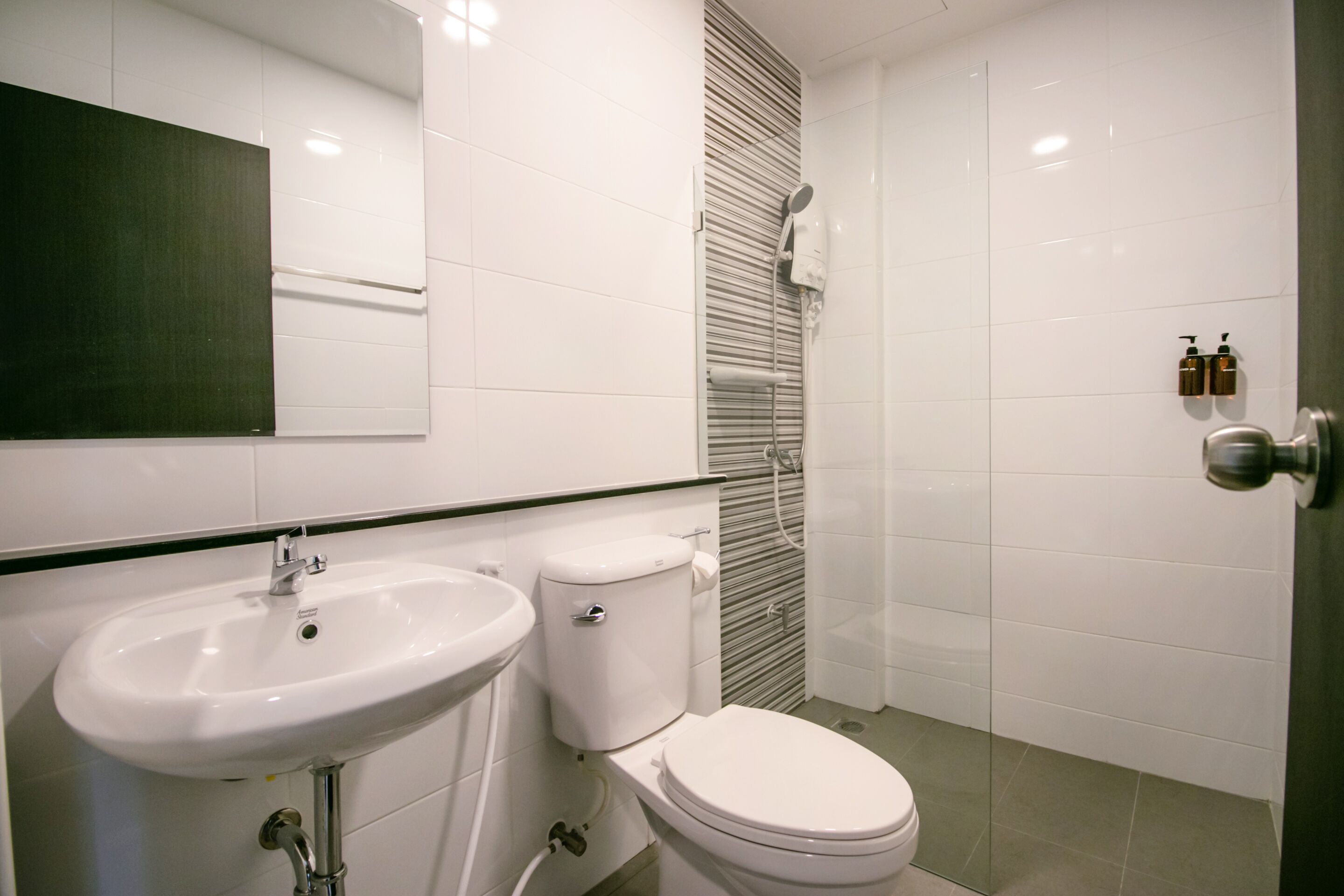 A modern bathroom with a white sink, toilet, and shower.