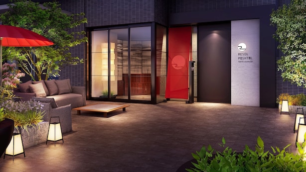 Un área de estar al aire libre con un sofá, una mesita y un paraguas rojo. Se observa un letrero del Resid Resort Hotel en Tokio Asakusa.