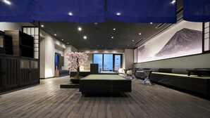 Un moderno vestíbulo de hotel con un amplio espacio para sentarse, un árbol decorativo y una obra de arte en la pared.