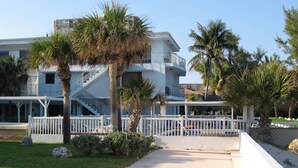 A two-story building with a white exterior, a covered outdoor area, and a pool. - Just steps to the Warm Sandy Beach of Southern Florida (Pompano Beach)