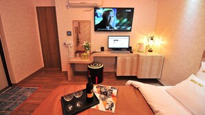 Une chambre d’hôtel équipée d’un lit, d’un bureau avec un ordinateur, d’une télévision et d’un mini-bar.