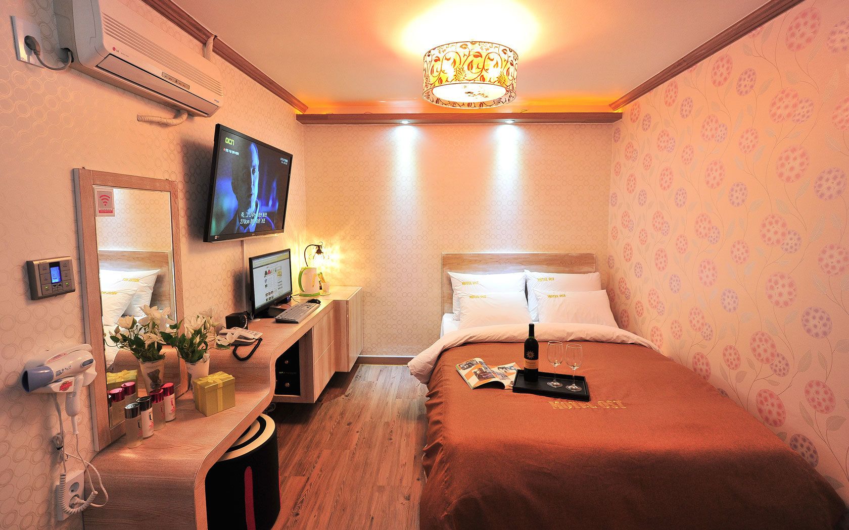 Ett hotellrum med en säng, ett skrivbord med en dator, en TV och en minibar.