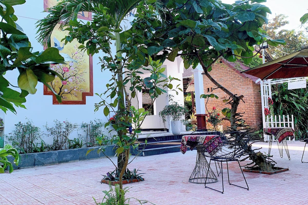 An outdoor patio area with a brick wall, potted plants, and a white fence.