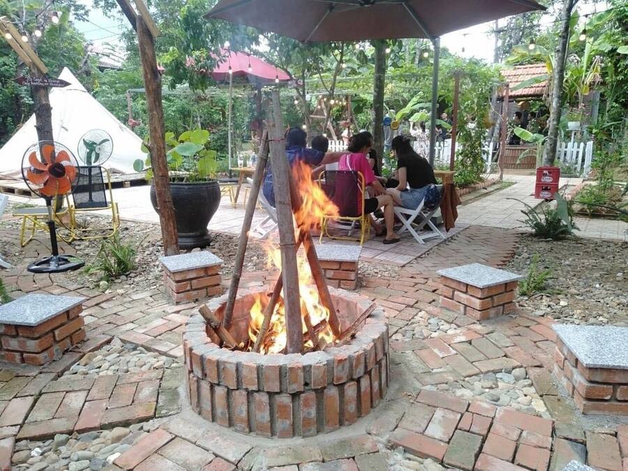 A fire pit surrounded by brick seating, with people gathered around it.