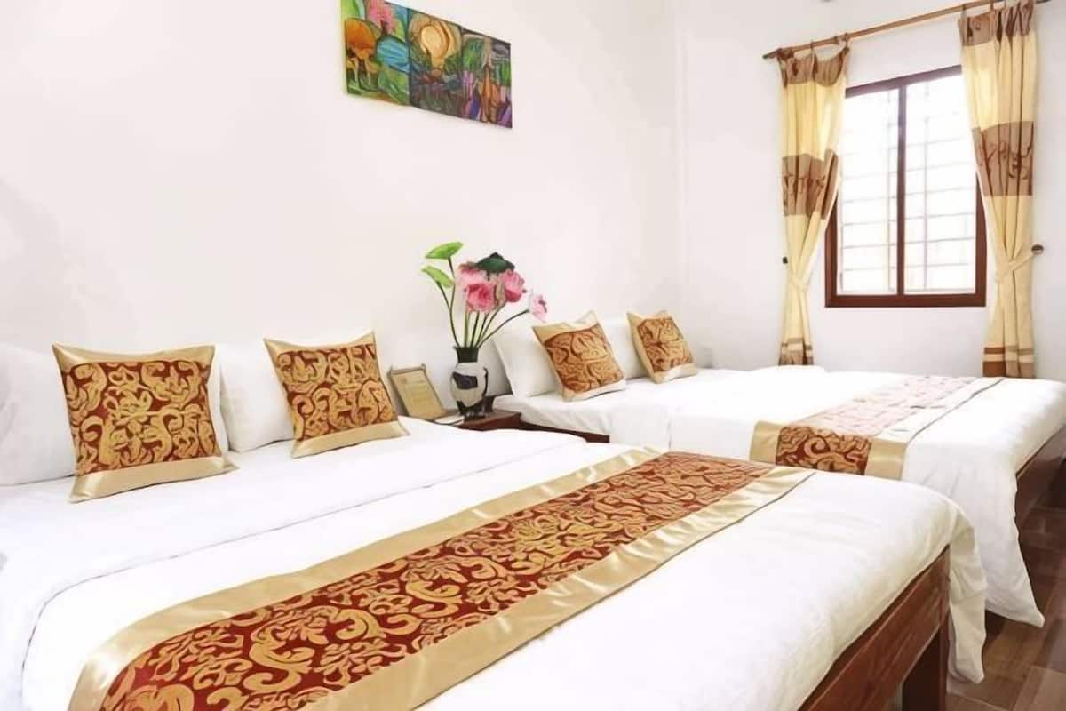 A hotel room with two beds, a vase with flowers, and a painting on the wall.