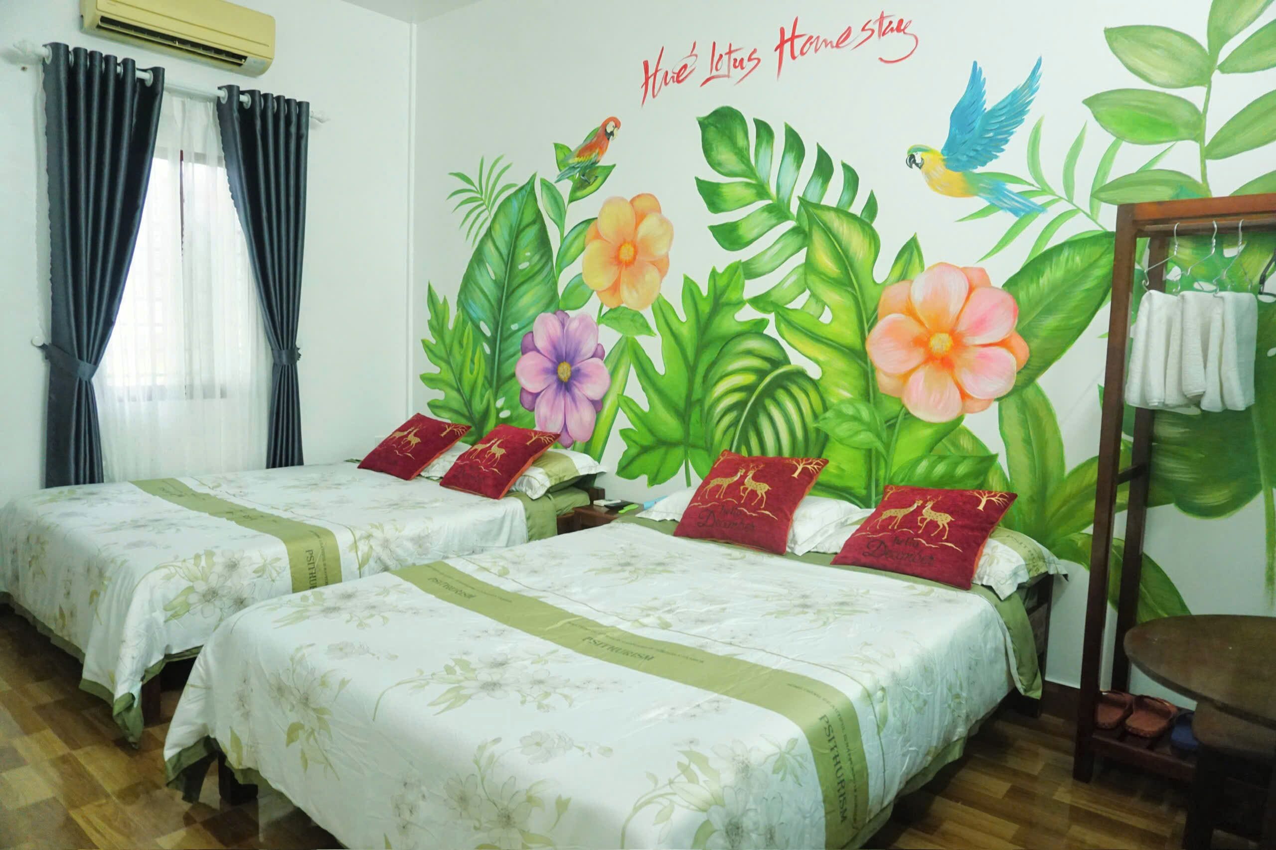 A hotel room with two beds, a mural of tropical flowers and birds, and a wooden chair.