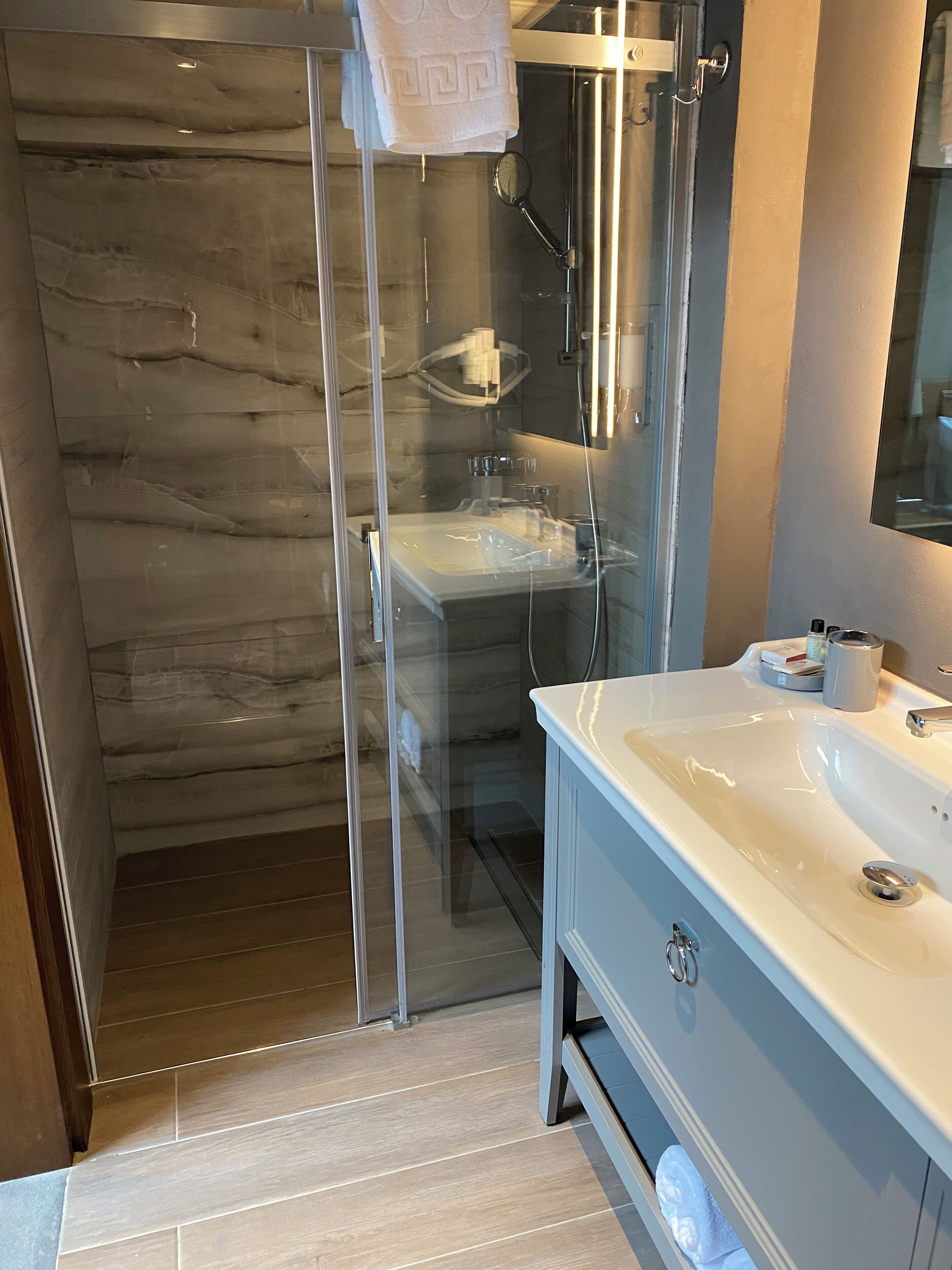 Une salle de bain moderne avec une douche à parois de verre, un lavabo blanc et un miroir.