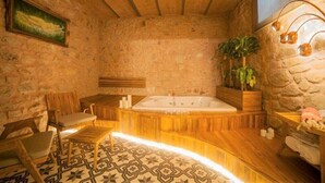 A stone-walled bathroom with a wooden bathtub, a wooden bench, and a patterned floor. - Triada Hotel Buyukada (Adalar)