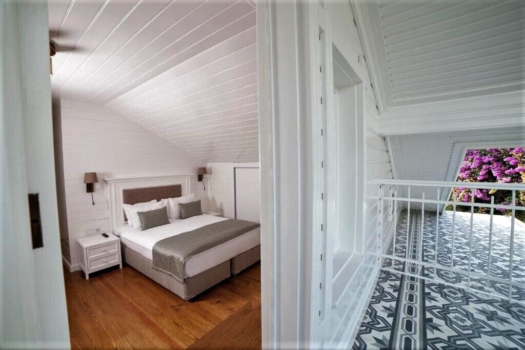 Un dormitorio con cama, mesita de noche y balcón con piso estampado.