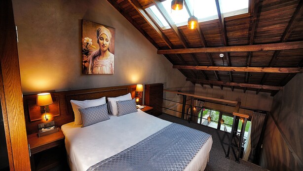 A spacious bedroom with a large bed, wooden ceiling beams, and a skylight. - Triada Hotel Buyukada (Adalar)