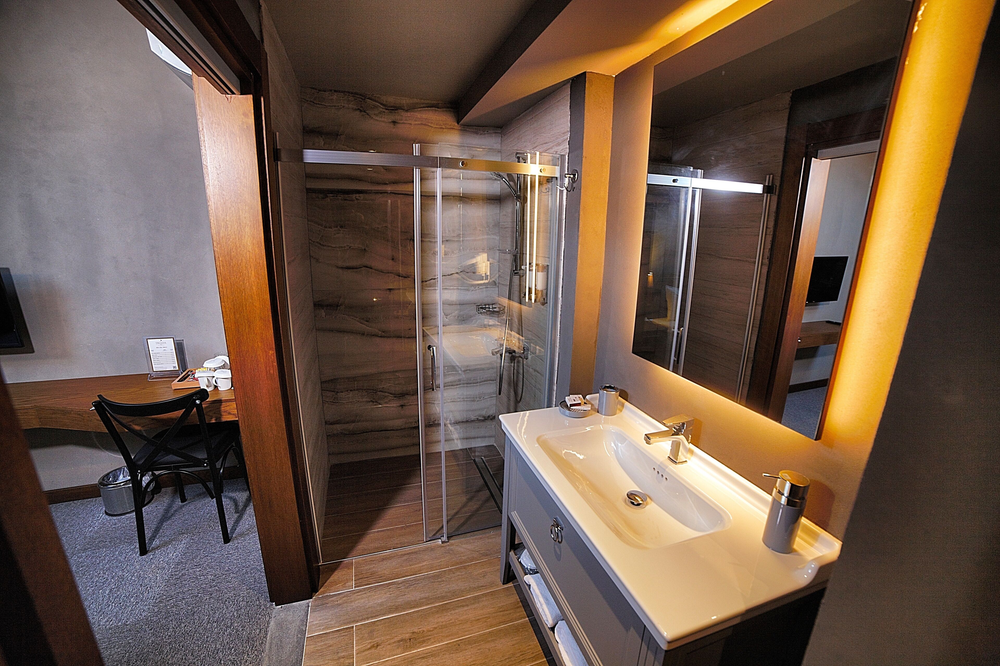 A modern bathroom with a glass shower enclosure, a large mirror, and a vanity with a sink.