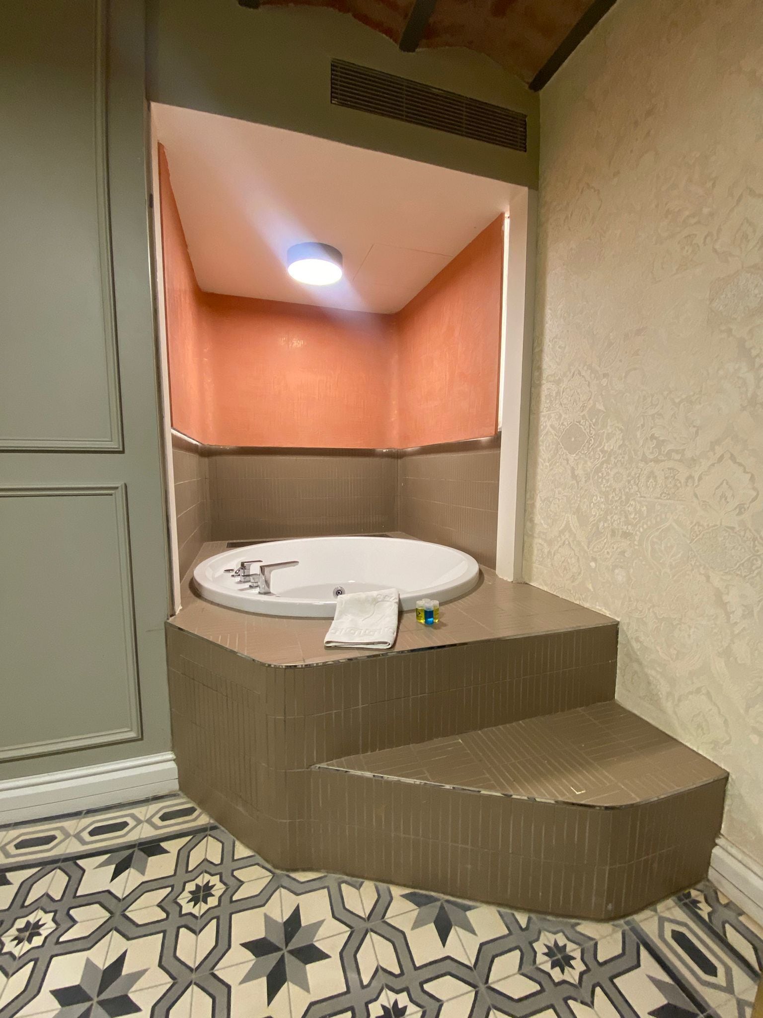 A bathroom with a freestanding bathtub, a towel, and a small bottle of shampoo.