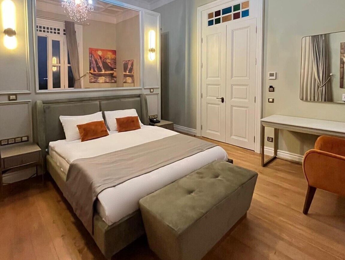 Un dormitorio con una cama, una mesita de noche, un banco, un escritorio y una silla.