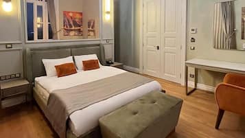 Un dormitorio con una cama, una mesita de noche, un banco, un escritorio y una silla.