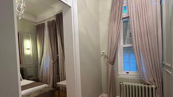 A bedroom with a bunk bed, a radiator, and a window with curtains.