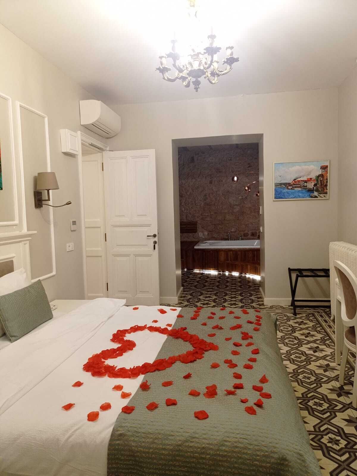 A hotel room with a bed, a chandelier, a painting, and a patterned floor.