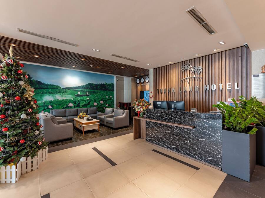 A hotel lobby with a reception desk, a Christmas tree, and a mural of a landscape.
