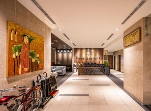 Un moderno vestíbulo de hotel con mostrador de recepción, zona de estar y un gran cuadro decorativo.