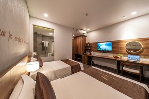 A hotel room with two beds, a desk with a laptop, a television, and a mirror.