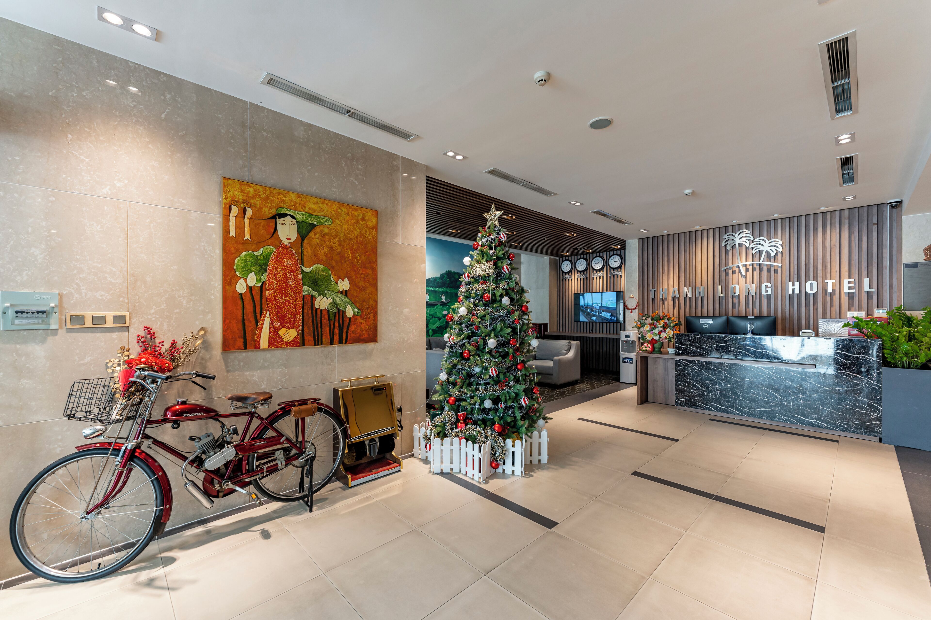 Un hall d’hôtel moderne avec un comptoir d’accueil, un sapin de Noël et un vélo d’époque.