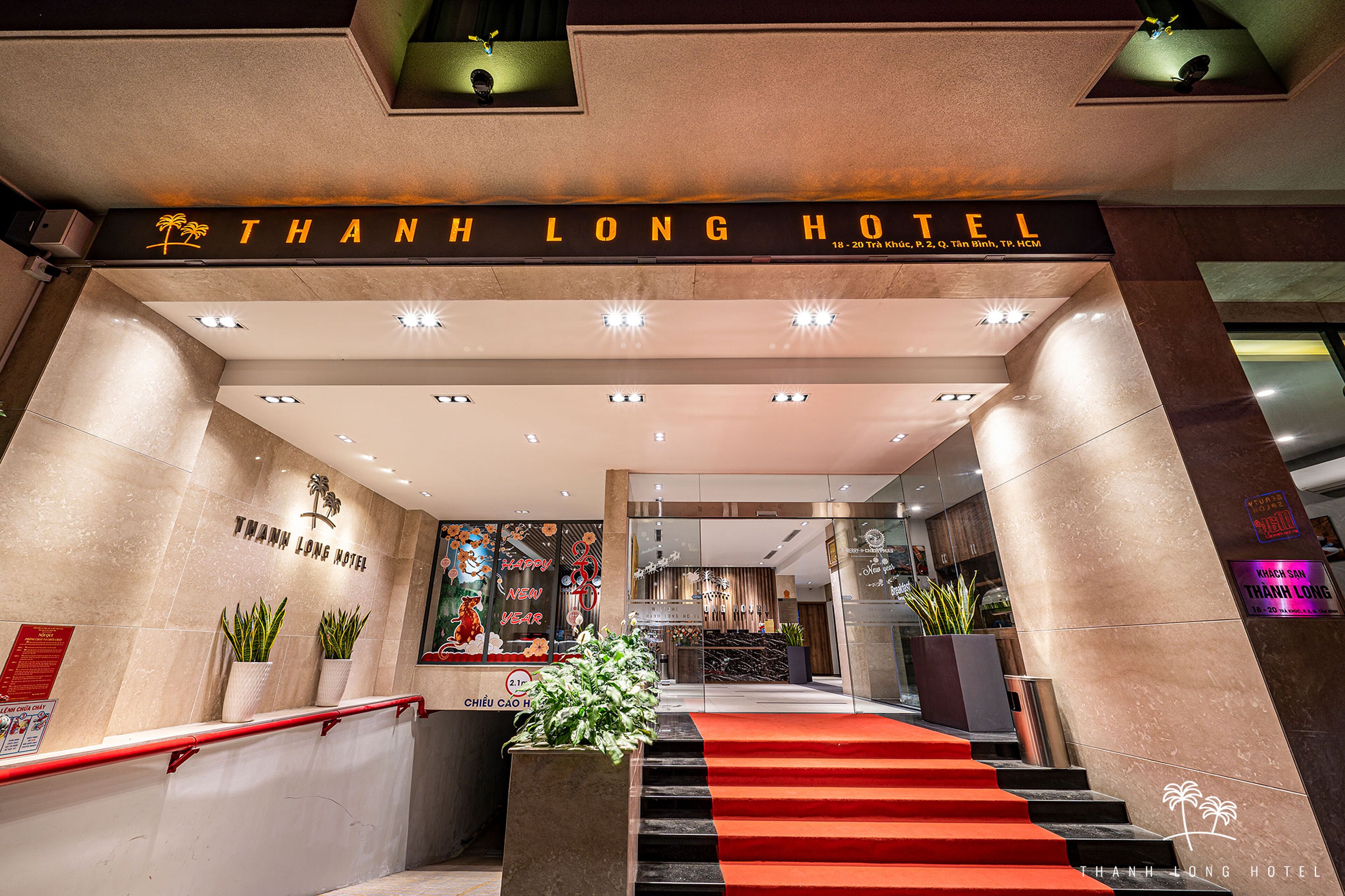 The entrance of Thanh Long Hotel with a red carpet, a staircase, and a sign above the entrance.