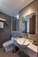 Un baño moderno con inodoro, lavamanos y espejo.