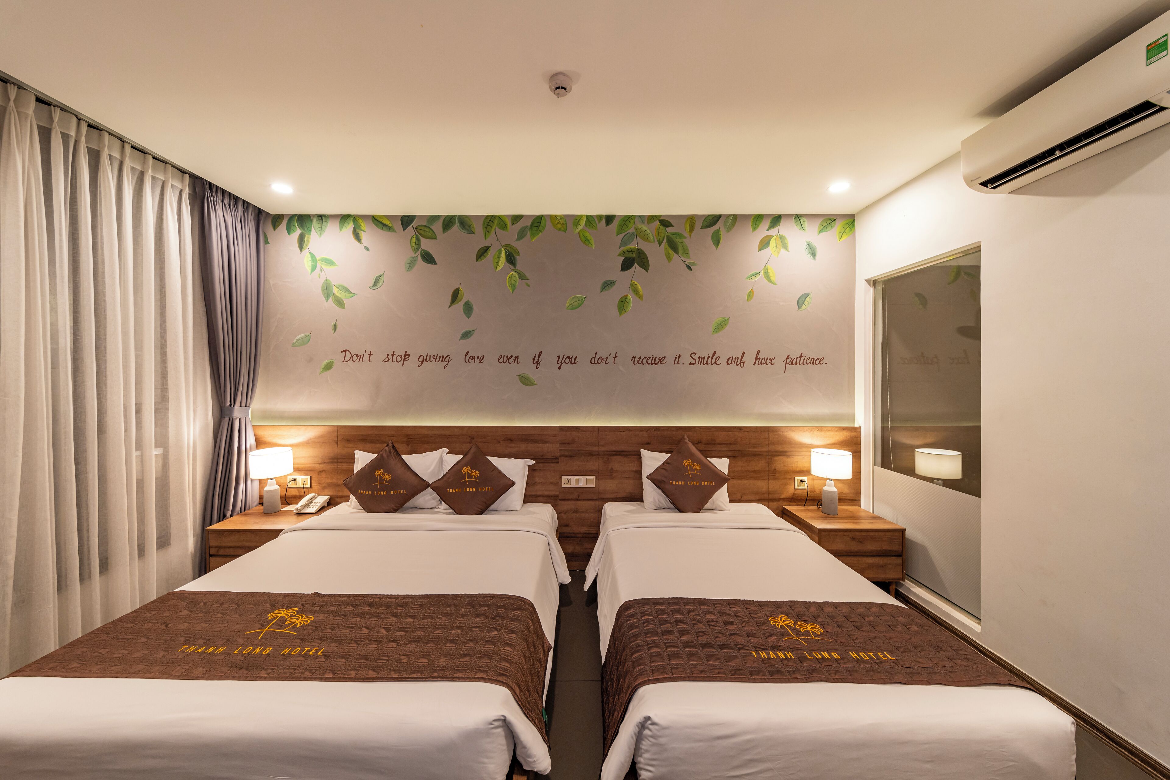 Habitación de hotel con dos camas, un espejo grande y una pared con una cita motivacional.