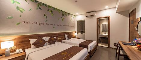 A hotel room with two beds, a desk, and a bathroom visible through an open door.