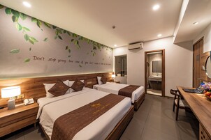 A hotel room with two beds, a desk, and a bathroom visible through an open door.