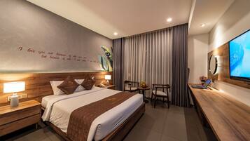 A modern hotel room with a large bed, bedside tables with lamps, a desk with a laptop, and a TV on the wall.