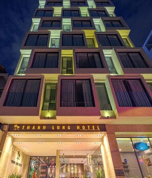 Fachada del Hotel Thanh Long de noche con señalización iluminada y un diseño arquitectónico moderno.
