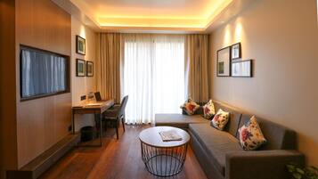 A modern living room with a sofa, coffee table, and a desk with a chair.