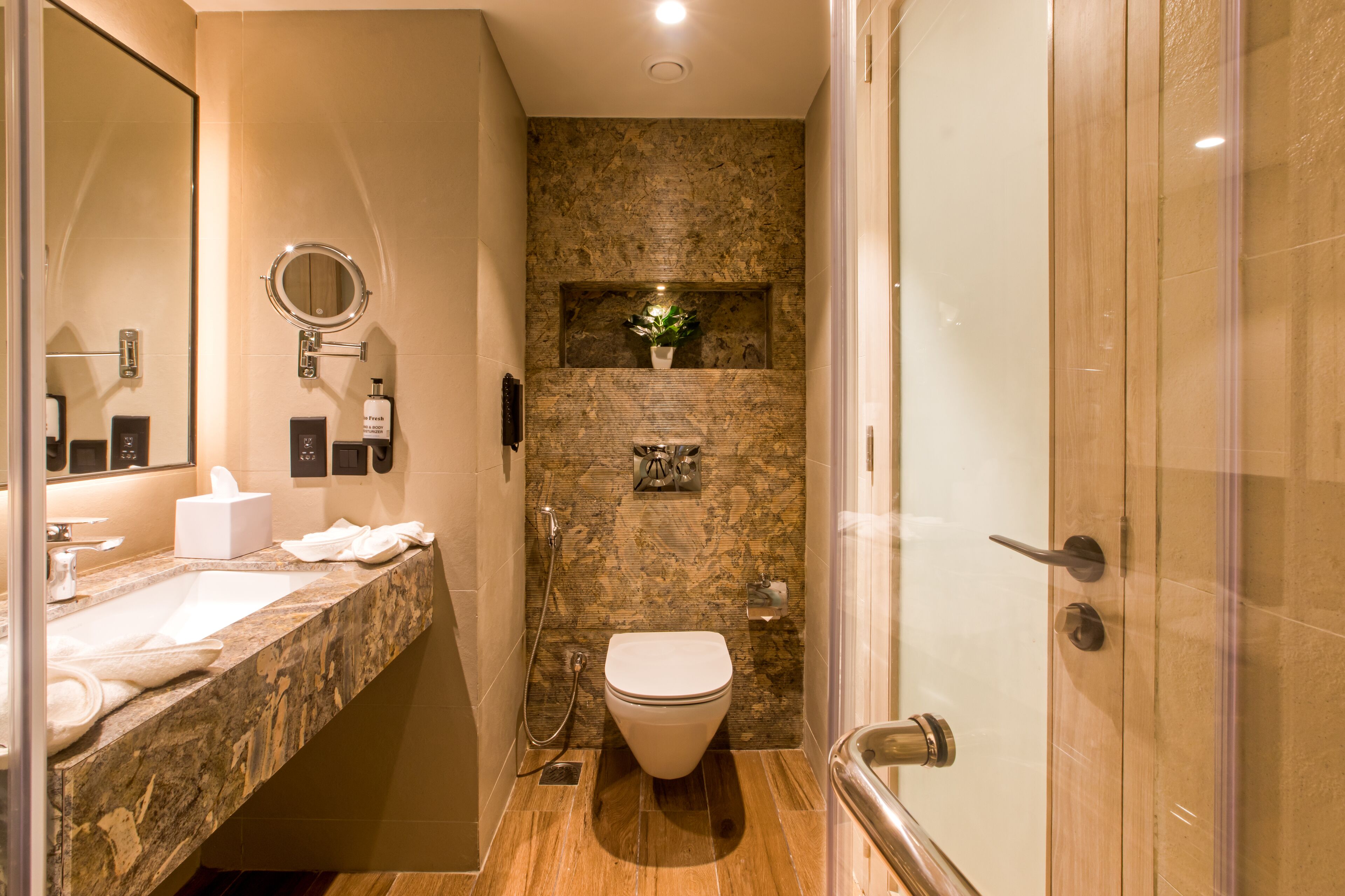 A modern bathroom with a marble sink, a toilet, and a shower area.