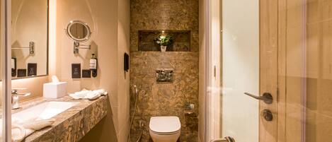 A modern bathroom with a marble sink, a toilet, and a shower area.