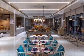 Un comedor moderno con mesas redondas, sillas azules y una barra central.