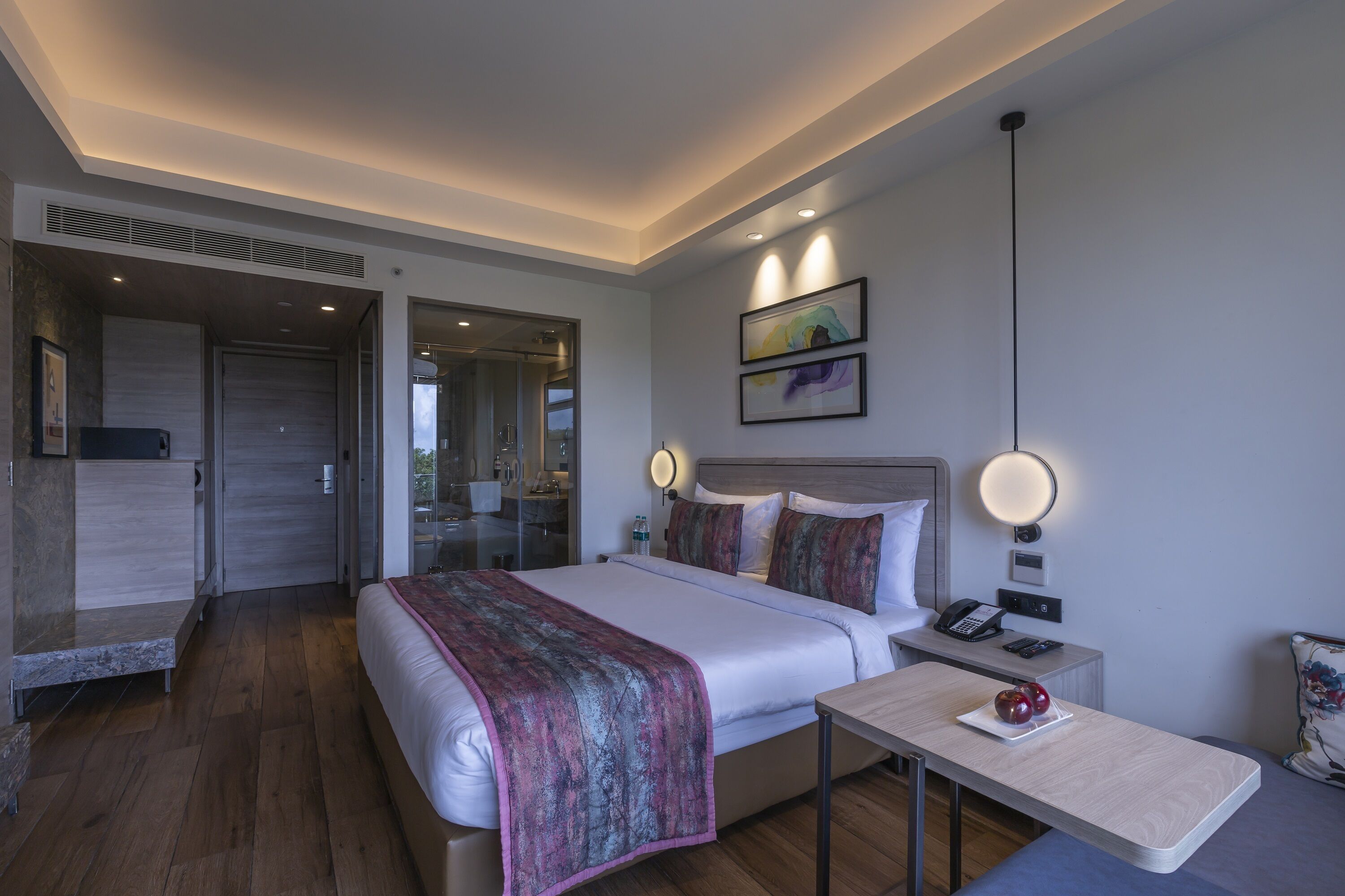 Una habitación de hotel moderna con una cama grande, mesitas de noche, un escritorio y un espejo.