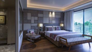 Une chambre d’hôtel moderne dotée d’un grand lit, de tables de chevet, d’un coin salon et offrant une vue sur l’extérieur.
