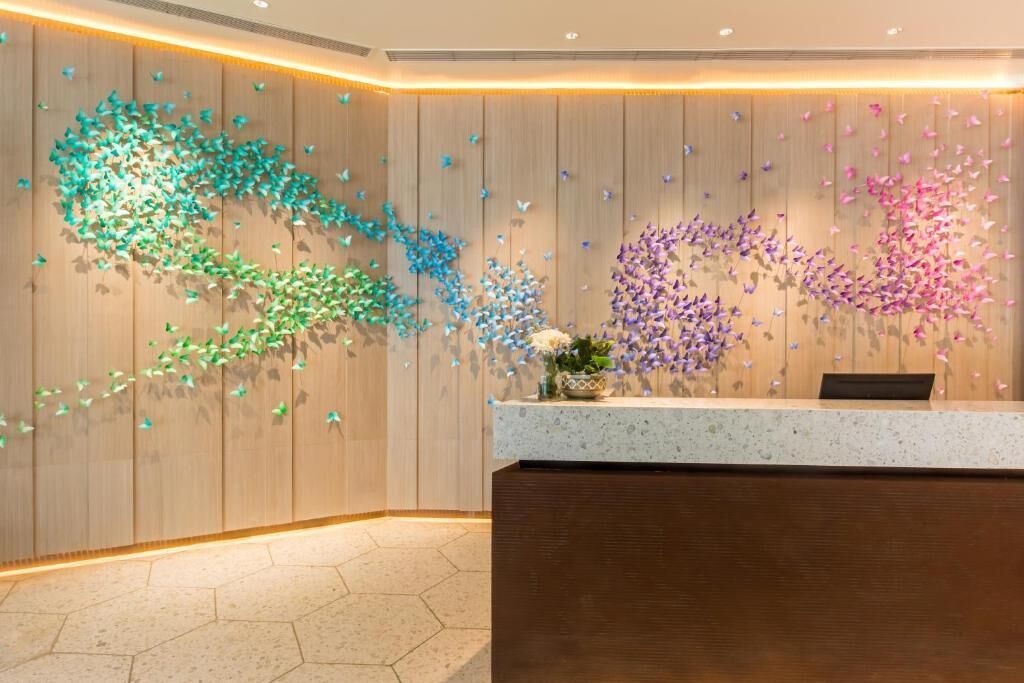A reception area with a wooden wall and a decorative butterfly installation.