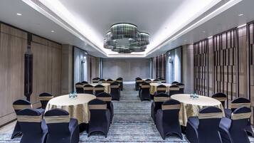 A conference room with round tables, chairs, and a modern chandelier.