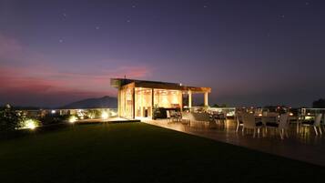 A modern outdoor dining area with a covered seating arrangement and a view of the mountains in the background.