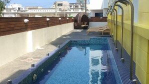 A rooftop swimming pool with a clear blue water feature, surrounded by a tiled deck and a wooden fence. - Dream Ocean View B&B (Magong)