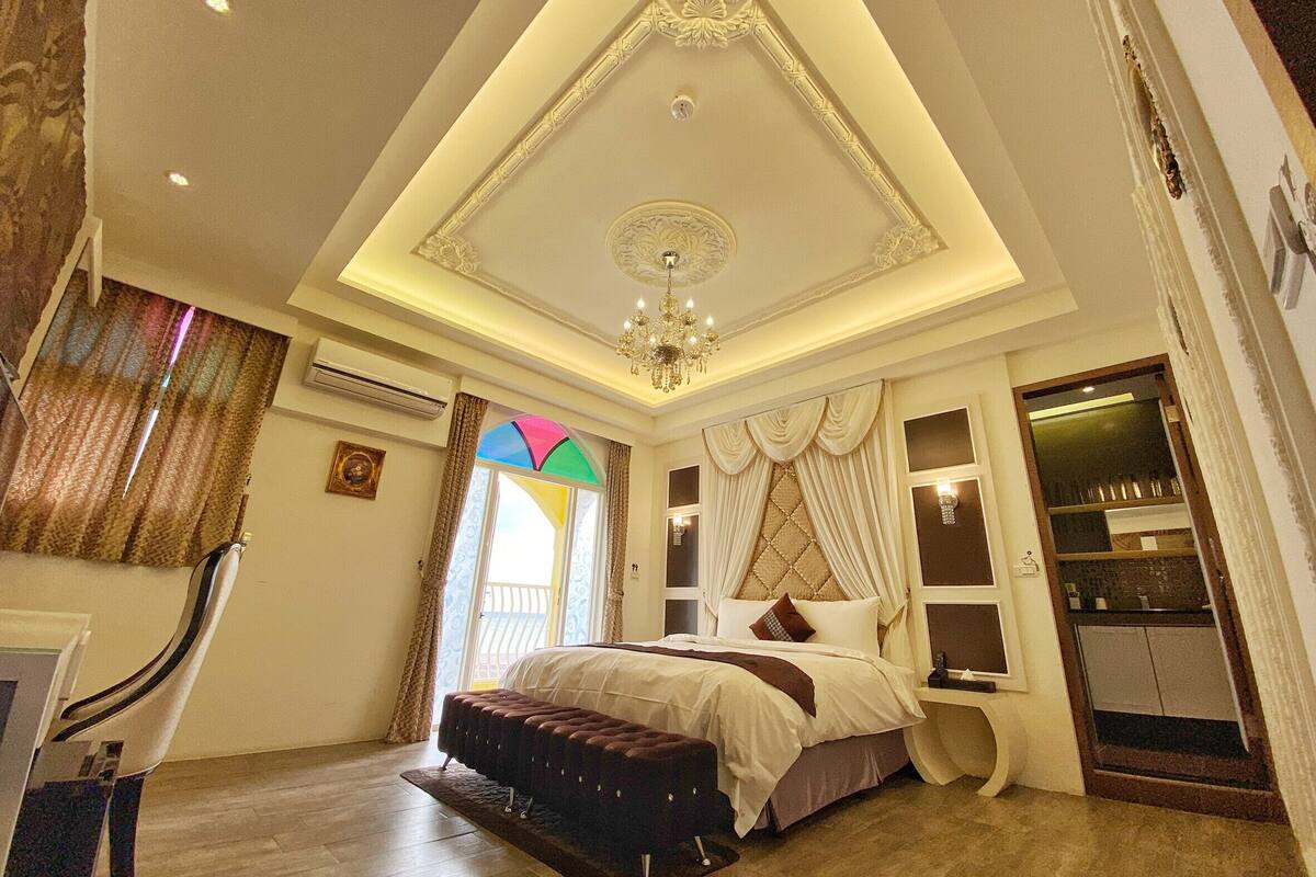 A bedroom with a large bed, a chandelier, and a built-in wardrobe.