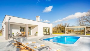 A modern house with a swimming pool, outdoor seating, and a covered patio area. - Villa Aida (Labin)