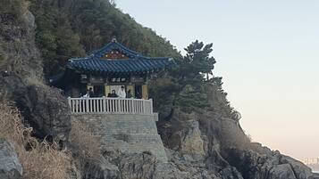 A traditional pavilion with a tiled roof, situated on a rocky hillside.
